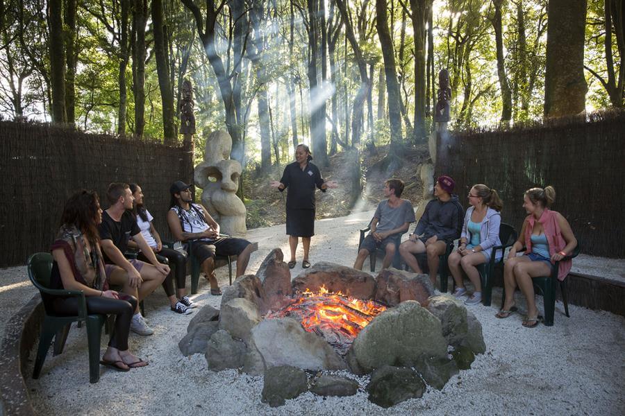 Image of people sat round the fire storytelling at Tamaki Maori Village