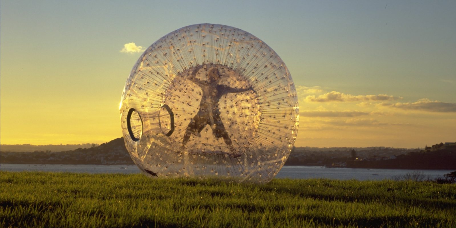 A person in a Zorb ball with Lake Rotorua in the background