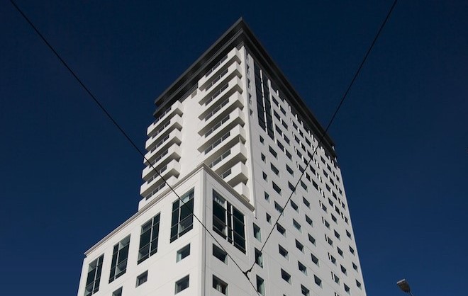 Photo looking up on tall hotel building with blue sky in the background.