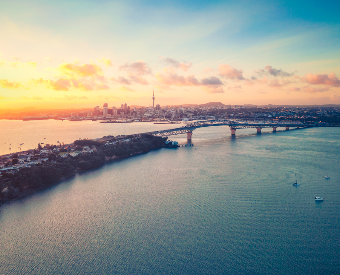 A high angle view of Auckland's sunrise, with the cityscape and Harbour Bridge seen across Waitemata Harbour.